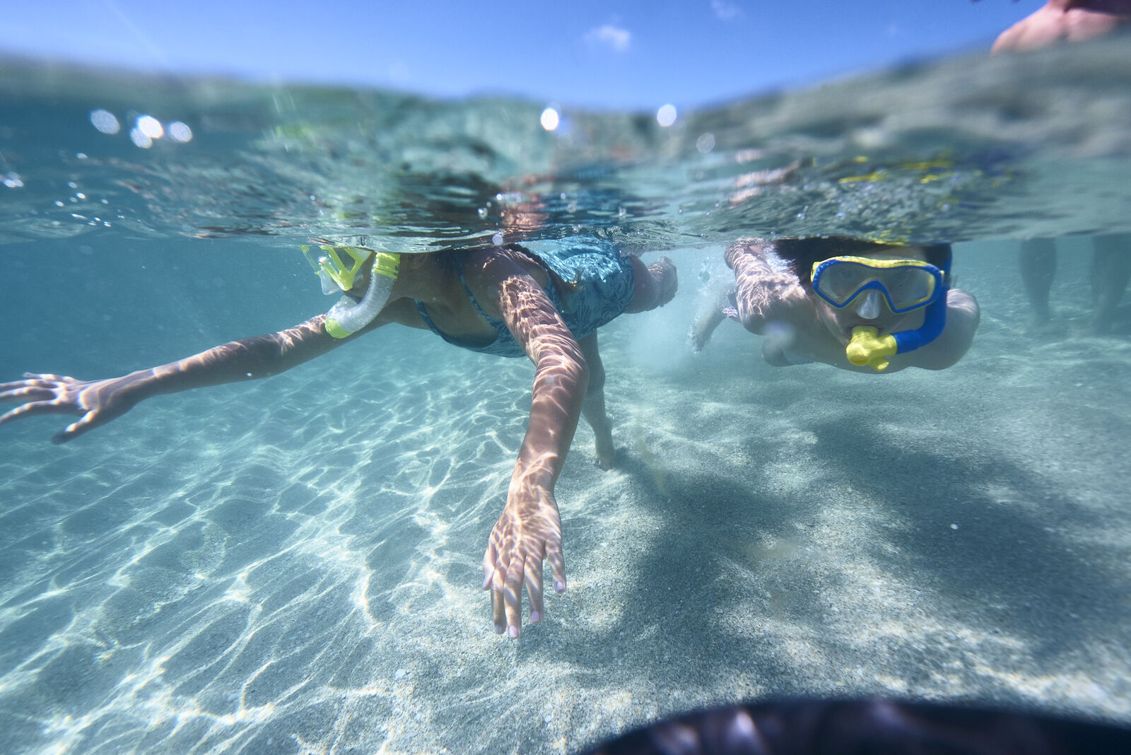 Two kids underwater, snorkeling in shallow water with a light sandy floor near our Palm beach luxury resort